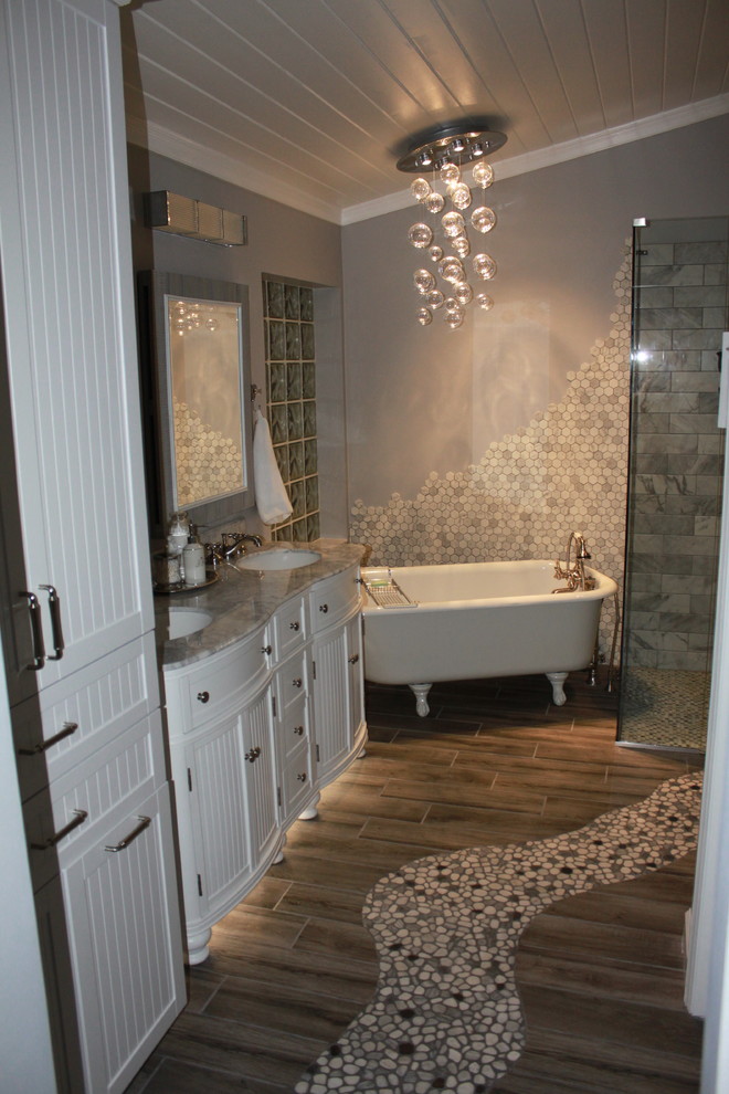 Inredning av ett lantligt mellanstort vit vitt en-suite badrum, med luckor med profilerade fronter, vita skåp, ett badkar med tassar, en kantlös dusch, en toalettstol med separat cisternkåpa, grå kakel, marmorkakel, grå väggar, klinkergolv i porslin, ett undermonterad handfat, marmorbänkskiva, grått golv och dusch med gångjärnsdörr