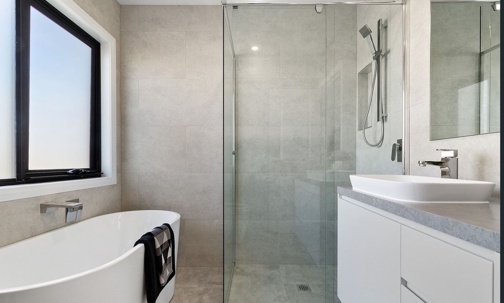 Medium sized modern bathroom in Melbourne with recessed-panel cabinets, white cabinets, a freestanding bath, a corner shower, grey tiles, porcelain tiles, grey walls, porcelain flooring, a submerged sink, engineered stone worktops, grey floors, a hinged door, grey worktops, a wall niche, a single sink and a built in vanity unit.