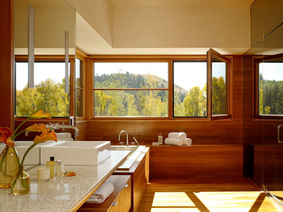 Ejemplo de cuarto de baño rectangular minimalista con lavabo sobreencimera, armarios con paneles lisos, puertas de armario de madera oscura, bañera encastrada y ducha empotrada