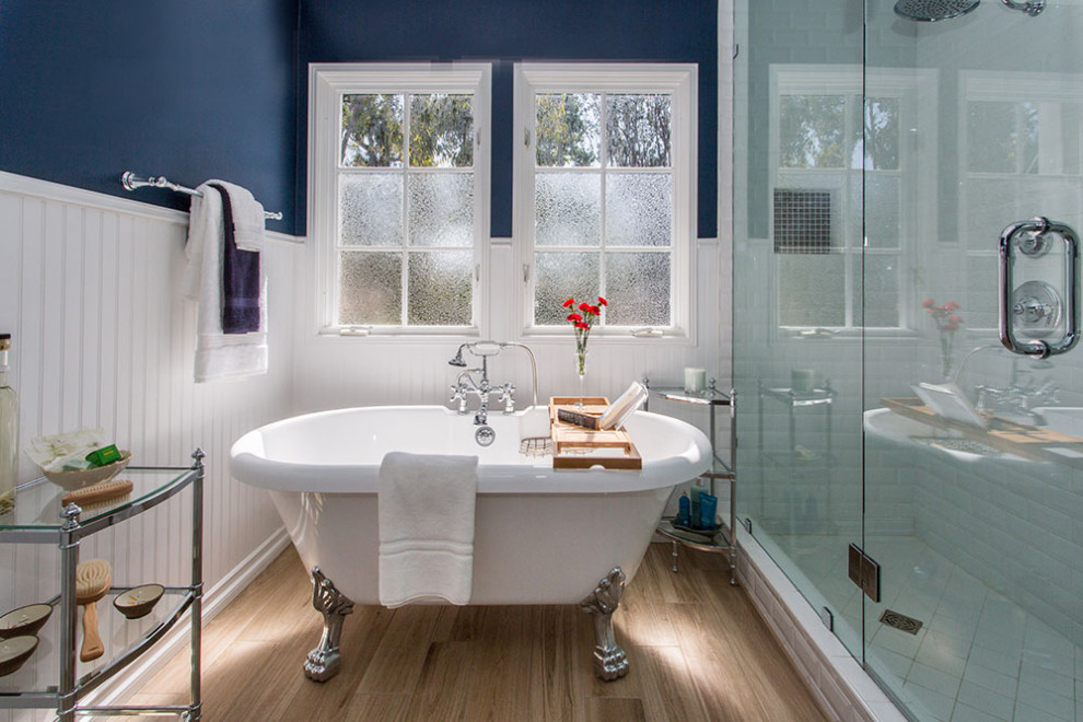 Свежая идея для дизайна: большая главная ванная комната в стиле модернизм с плоскими фасадами, белыми фасадами, ванной на ножках, душевой комнатой, синей плиткой, синими стенами, полом из ламината, настольной раковиной, столешницей из гранита, коричневым полом, душем с распашными дверями и белой столешницей - отличное фото интерьера