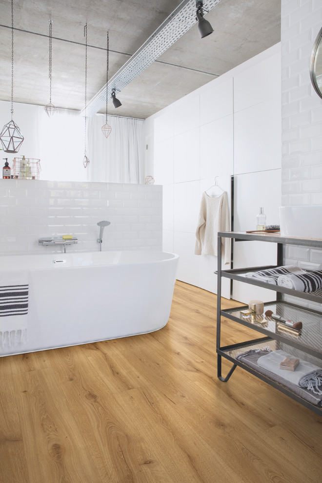 Ispirazione per una stanza da bagno padronale moderna di medie dimensioni con vasca freestanding, pareti bianche, pavimento in laminato e pavimento beige