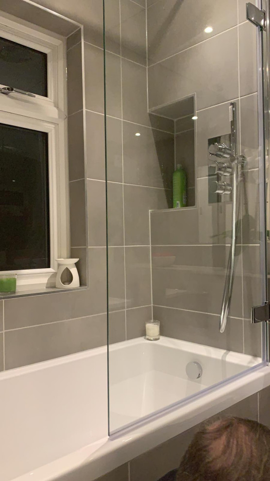 Ispirazione per una stanza da bagno per bambini minimal di medie dimensioni con ante lisce, ante grigie, vasca da incasso, vasca/doccia, WC sospeso, piastrelle grigie, piastrelle in gres porcellanato, pareti grigie, pavimento in gres porcellanato, lavabo a consolle, top in quarzo composito, pavimento grigio, porta doccia a battente, top bianco, nicchia, un lavabo e mobile bagno incassato
