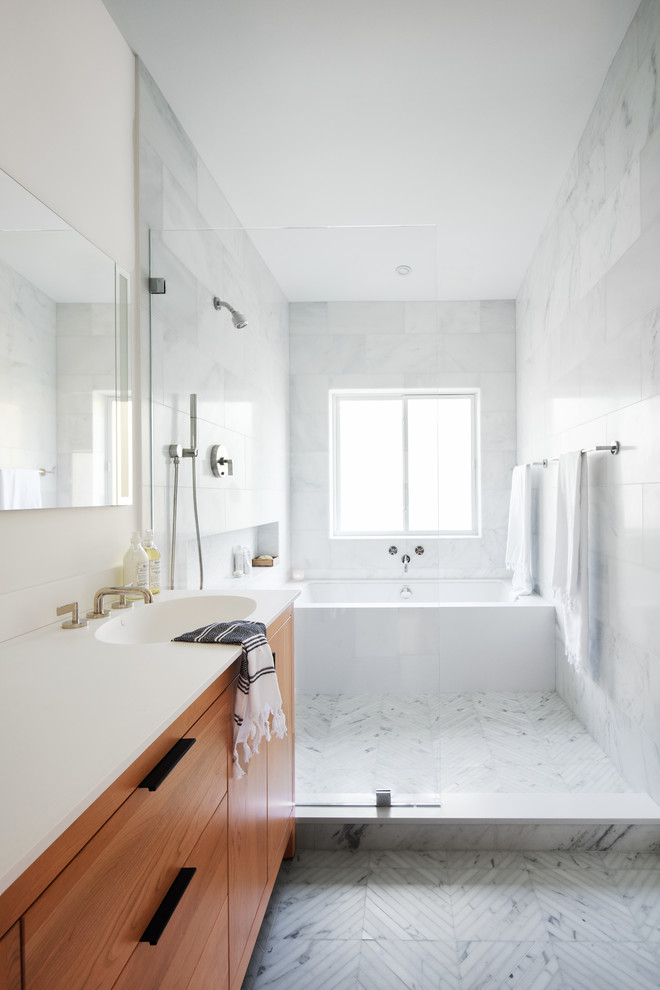 Пример оригинального дизайна: главная ванная комната среднего размера в стиле модернизм с фасадами цвета дерева среднего тона, полновстраиваемой ванной, открытым душем, унитазом-моноблоком, белой плиткой, каменной плиткой, белыми стенами, мраморным полом, монолитной раковиной, столешницей из искусственного кварца, белым полом, открытым душем, белой столешницей и плоскими фасадами