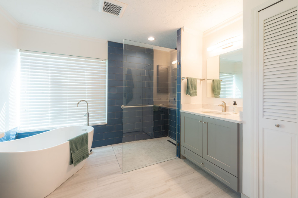 На фото: ванная комната в стиле модернизм с фасадами с утопленной филенкой, серыми фасадами, японской ванной, душевой комнатой, синей плиткой, керамической плиткой, белыми стенами, полом из ламината, разноцветным полом, открытым душем, тумбой под одну раковину и встроенной тумбой с