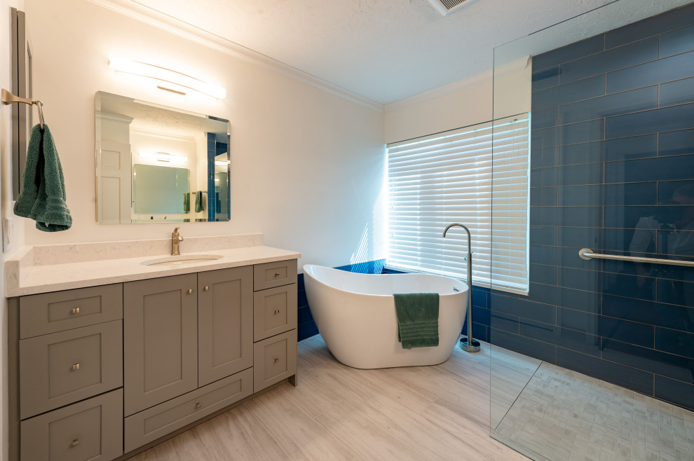 Inredning av ett modernt badrum, med luckor med infälld panel, grå skåp, ett japanskt badkar, våtrum, blå kakel, keramikplattor, vita väggar, laminatgolv, flerfärgat golv och med dusch som är öppen