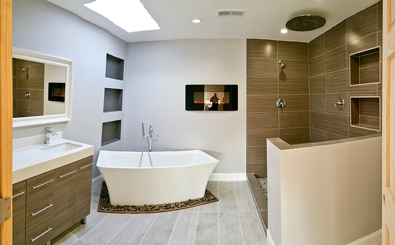 Cette photo montre une grande salle de bain principale moderne avec un lavabo encastré, un plan de toilette en quartz, une baignoire indépendante, une douche ouverte, un carrelage gris, une plaque de galets, un mur gris et un sol en carrelage de porcelaine.