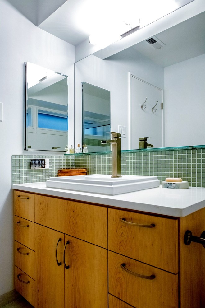 Photo of a small modern bathroom in Raleigh with green tiles, glass tiles, white walls, a built-in sink, solid surface worktops, flat-panel cabinets and medium wood cabinets.