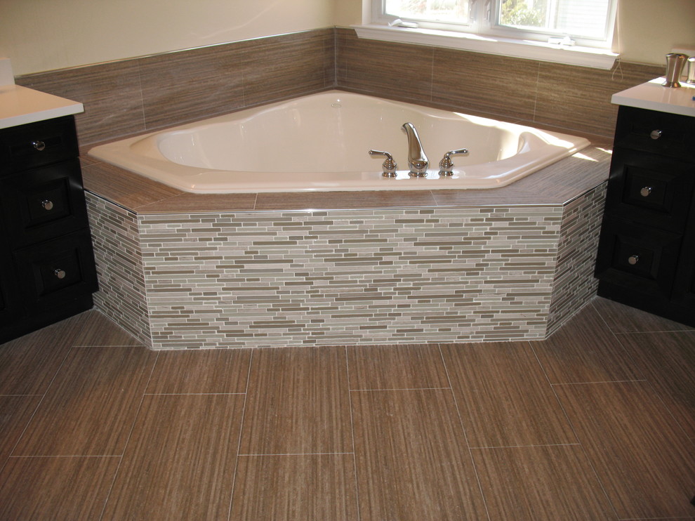 Example of a large trendy master beige tile and matchstick tile porcelain tile corner bathtub design in Newark with furniture-like cabinets, black cabinets, beige walls and solid surface countertops