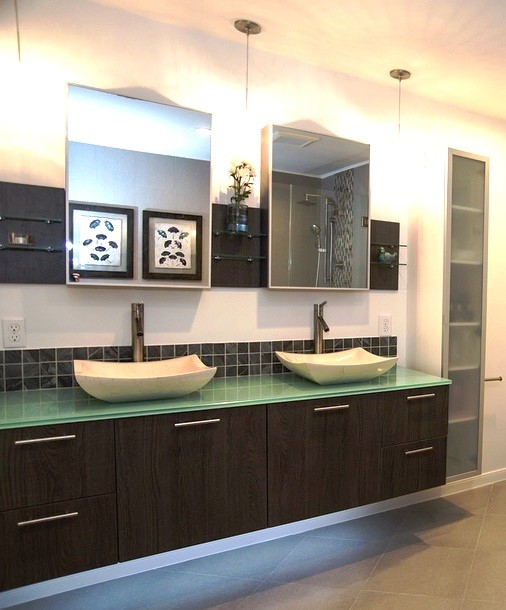 Bild på ett mellanstort funkis en-suite badrum, med ett fristående handfat, släta luckor, skåp i mörkt trä, bänkskiva i glas, ett undermonterat badkar, en kantlös dusch, grå kakel, porslinskakel, vita väggar och klinkergolv i keramik
