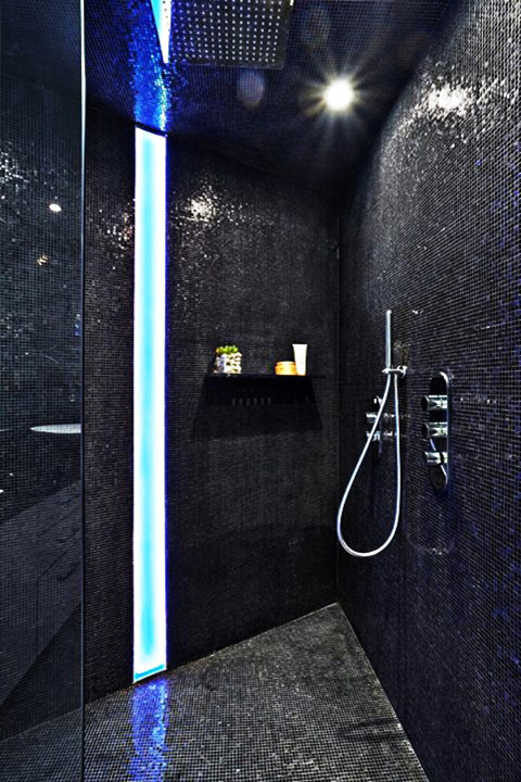 This is an example of a large modern ensuite bathroom in Miami with a walk-in shower, black tiles, glass tiles, black walls and mosaic tile flooring.