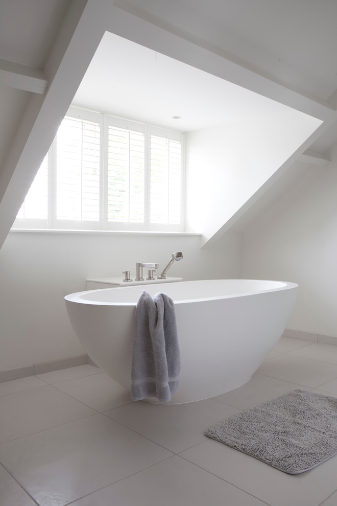 Стильный дизайн: серо-белая ванная комната в стиле модернизм с отдельно стоящей ванной и белыми стенами - последний тренд