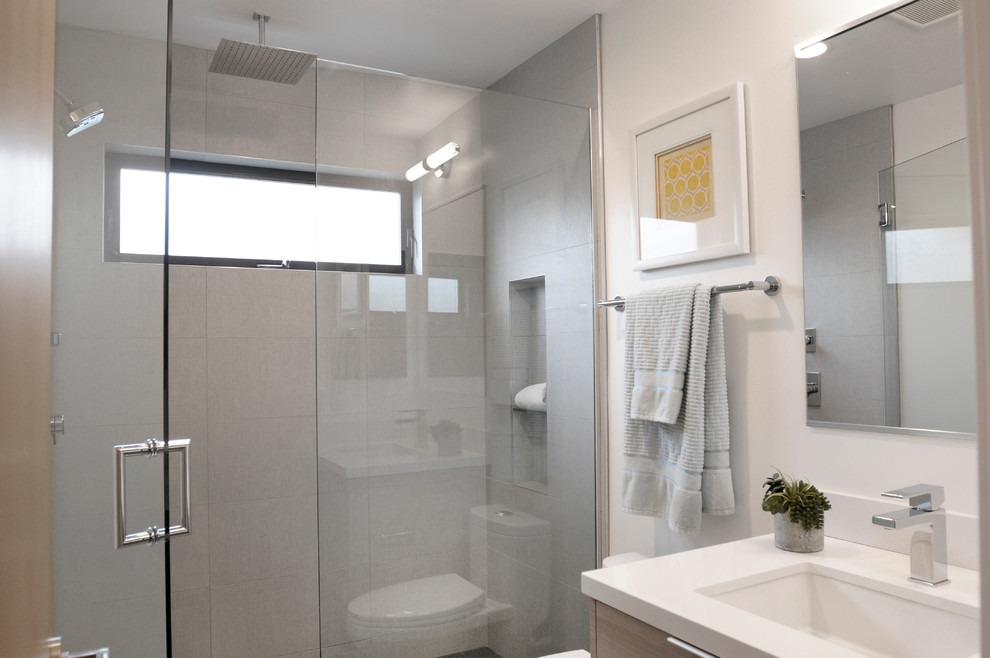 Aménagement d'une salle de bain moderne en bois clair de taille moyenne avec un lavabo encastré, un placard à porte plane, un plan de toilette en quartz modifié, WC à poser, un carrelage gris, des carreaux de porcelaine, un mur blanc et un sol en carrelage de porcelaine.