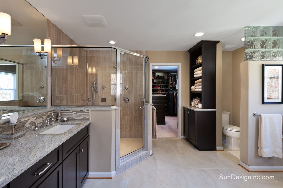 Cette image montre une salle de bain principale minimaliste en bois foncé avec un placard à porte shaker, un lavabo encastré, un plan de toilette en granite, une baignoire posée, une douche d'angle, WC séparés, un carrelage blanc et un mur beige.