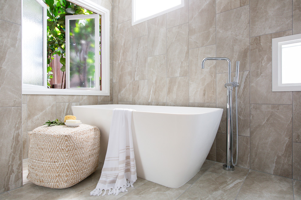 Ejemplo de cuarto de baño actual con puertas de armario de madera en tonos medios, bañera exenta, baldosas y/o azulejos de porcelana y suelo de baldosas de porcelana