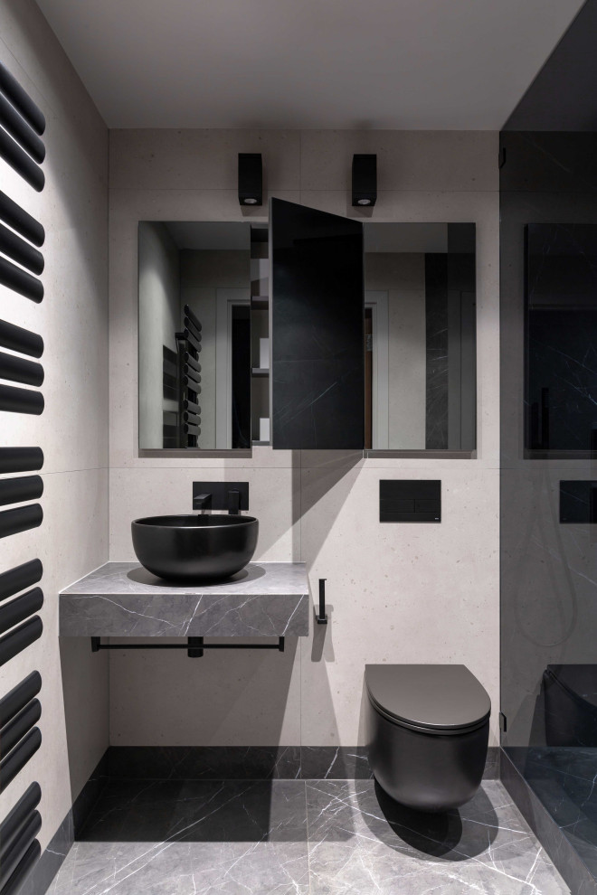 Photo of a medium sized contemporary shower room bathroom in London with glass-front cabinets, grey cabinets, a walk-in shower, a wall mounted toilet, grey tiles, ceramic tiles, beige walls, ceramic flooring, a vessel sink, tiled worktops, grey floors, a hinged door and grey worktops.