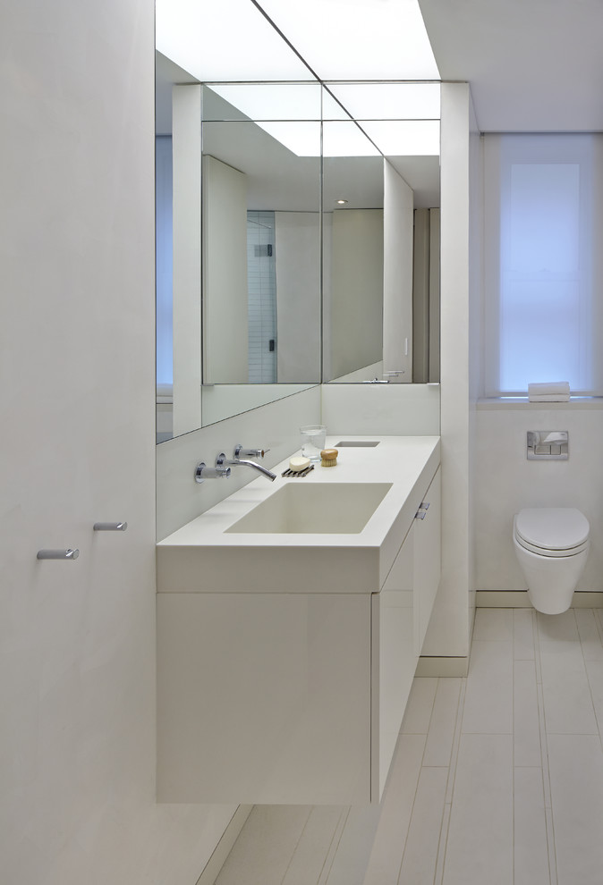 Mid-sized minimalist kids' white tile and porcelain tile porcelain tile corner shower photo in New York with an integrated sink, flat-panel cabinets, white cabinets, a wall-mount toilet and white walls