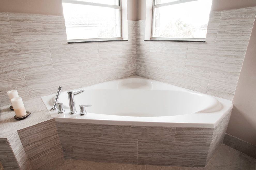 Cette image montre une salle de bain minimaliste avec une vasque, un placard à porte shaker, des portes de placard blanches, un plan de toilette en quartz, une baignoire d'angle, une douche à l'italienne, WC à poser, un carrelage gris et des carreaux de porcelaine.