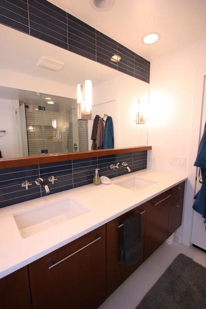 Стильный дизайн: большая ванная комната в стиле модернизм с врезной раковиной, плоскими фасадами, темными деревянными фасадами, столешницей из искусственного кварца, угловым душем, синей плиткой, керамической плиткой, белыми стенами, полом из керамогранита и душевой кабиной - последний тренд