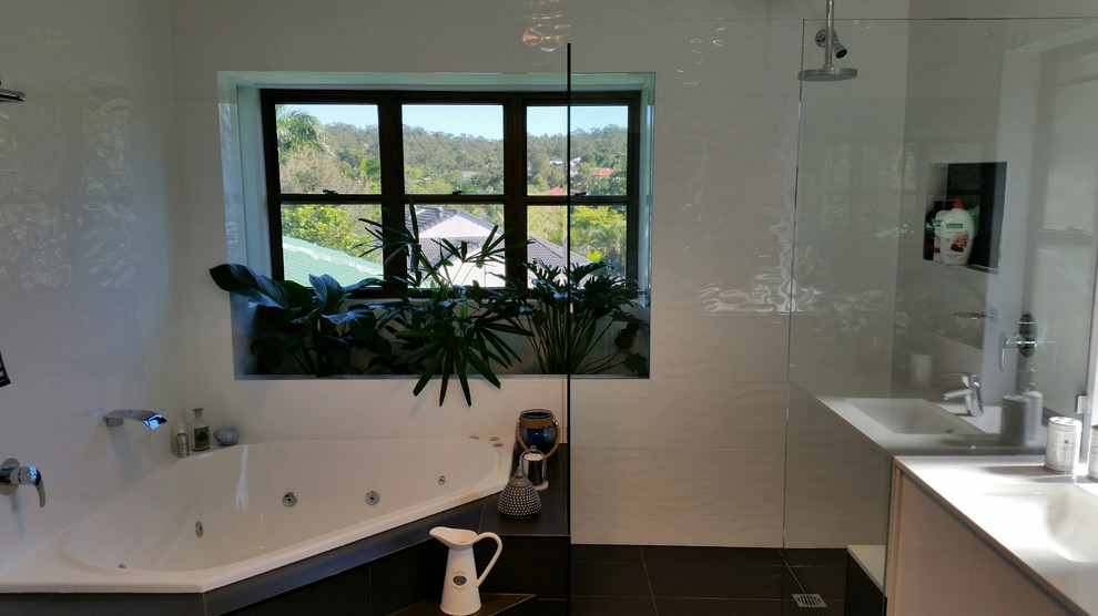 Design ideas for a medium sized contemporary ensuite bathroom in Brisbane with flat-panel cabinets, a hot tub, a corner shower, white tiles, porcelain tiles, ceramic flooring, an integrated sink, black floors and an open shower.