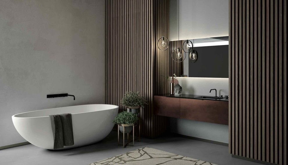 Cette photo montre une grande salle de bain principale moderne avec un placard à porte plane, une baignoire indépendante, un mur gris, un lavabo intégré, un sol gris et un plan de toilette noir.
