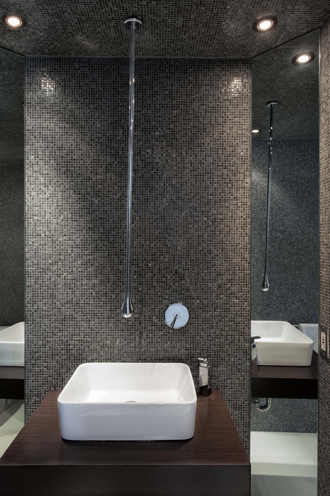 Foto di una stanza da bagno padronale minimalista di medie dimensioni con lavabo a bacinella, ante in legno bruno, top in legno, WC a due pezzi, piastrelle grigie, piastrelle di vetro e pareti grigie