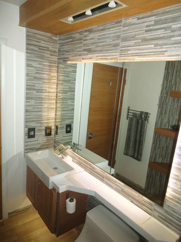 Inredning av ett asiatiskt mellanstort vit vitt badrum med dusch, med släta luckor, bruna skåp, en toalettstol med hel cisternkåpa, grå kakel, porslinskakel, grå väggar, vinylgolv, ett avlångt handfat, kaklad bänkskiva och beiget golv
