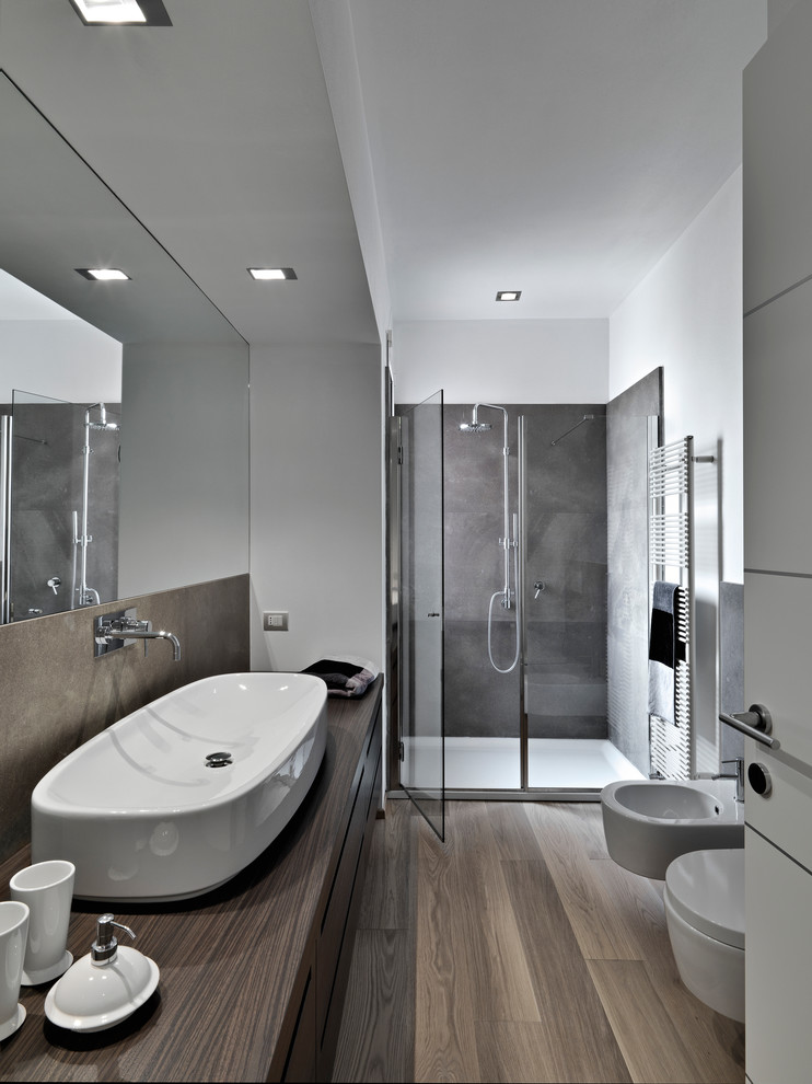 Пример оригинального дизайна: ванная комната среднего размера в стиле модернизм с плоскими фасадами, темными деревянными фасадами, душем в нише, биде, белыми стенами, полом из ламината, настольной раковиной, столешницей из дерева, душем с распашными дверями и коричневой столешницей