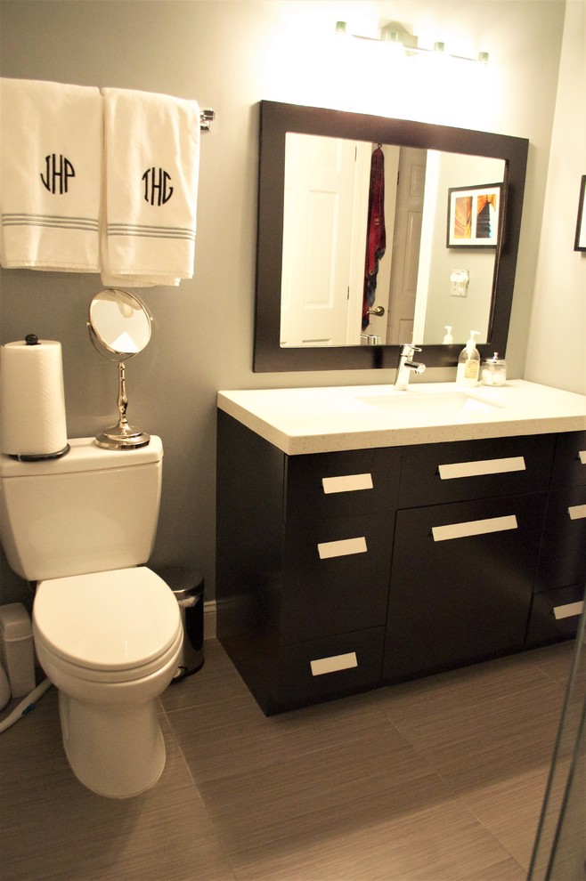 На фото: ванная комната среднего размера в современном стиле с плоскими фасадами, черными фасадами, раздельным унитазом, серыми стенами, полом из керамогранита, душевой кабиной, врезной раковиной и коричневым полом