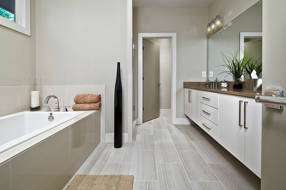 Стильный дизайн: большая главная ванная комната в стиле модернизм с врезной раковиной, плоскими фасадами, белыми фасадами, столешницей из искусственного кварца, накладной ванной, двойным душем, раздельным унитазом, серой плиткой, керамогранитной плиткой, серыми стенами и полом из керамогранита - последний тренд