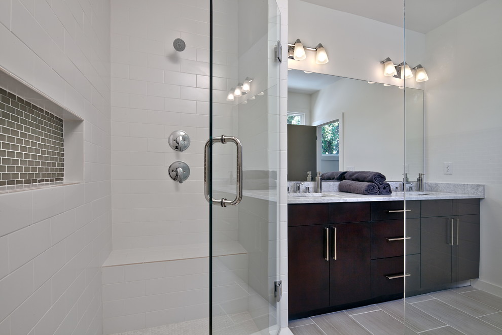 Réalisation d'une salle de bain principale minimaliste en bois foncé de taille moyenne avec un lavabo encastré, un placard à porte plane, un plan de toilette en marbre, une douche double, un carrelage gris et un mur blanc.