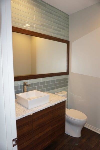 Kleines Modernes Duschbad mit flächenbündigen Schrankfronten, dunklen Holzschränken, braunem Boden, Toilette mit Aufsatzspülkasten, grauen Fliesen, Glasfliesen, grauer Wandfarbe, dunklem Holzboden, Aufsatzwaschbecken und Recyclingglas-Waschtisch in Indianapolis