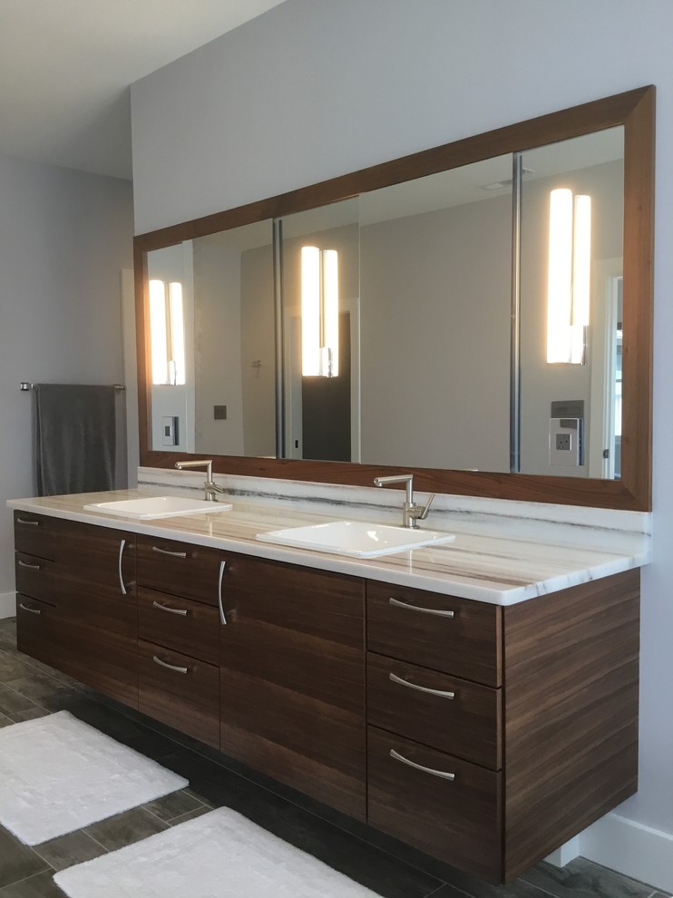 Réalisation d'une grande salle de bain principale minimaliste en bois foncé avec un placard à porte plane, une baignoire indépendante, un mur blanc, un sol en vinyl, une vasque et un sol marron.