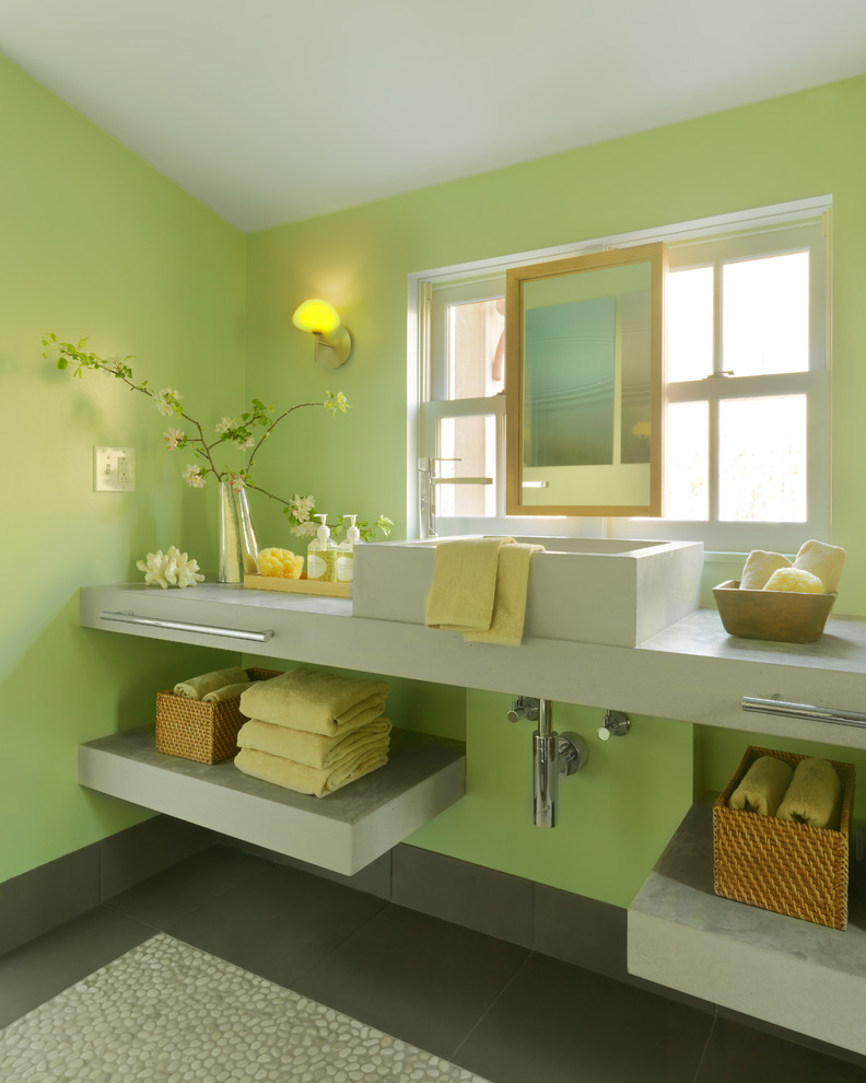 Modern inredning av ett litet en-suite badrum, med gröna väggar, ett fristående handfat, bänkskiva i kvarts, en kantlös dusch, en toalettstol med hel cisternkåpa och klinkergolv i småsten