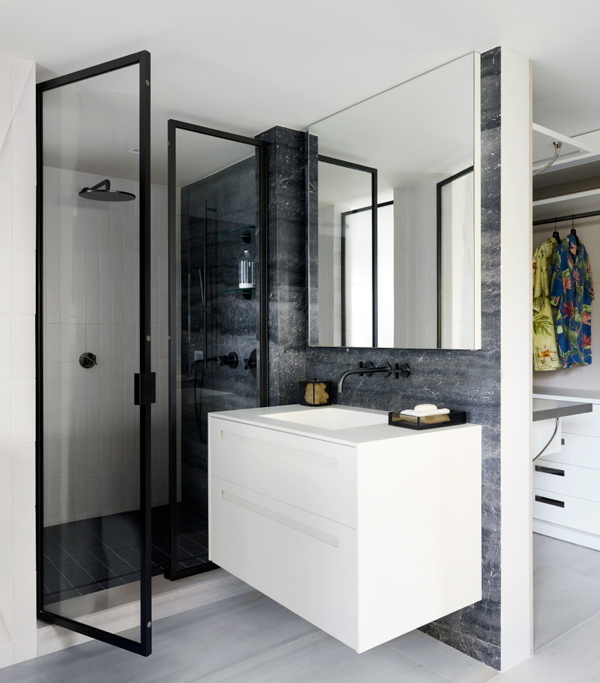 Идея дизайна: ванная комната в современном стиле с плоскими фасадами, белыми фасадами, угловым душем, серой плиткой, белой плиткой, серыми стенами, монолитной раковиной, бежевым полом, душем с распашными дверями и белой столешницей