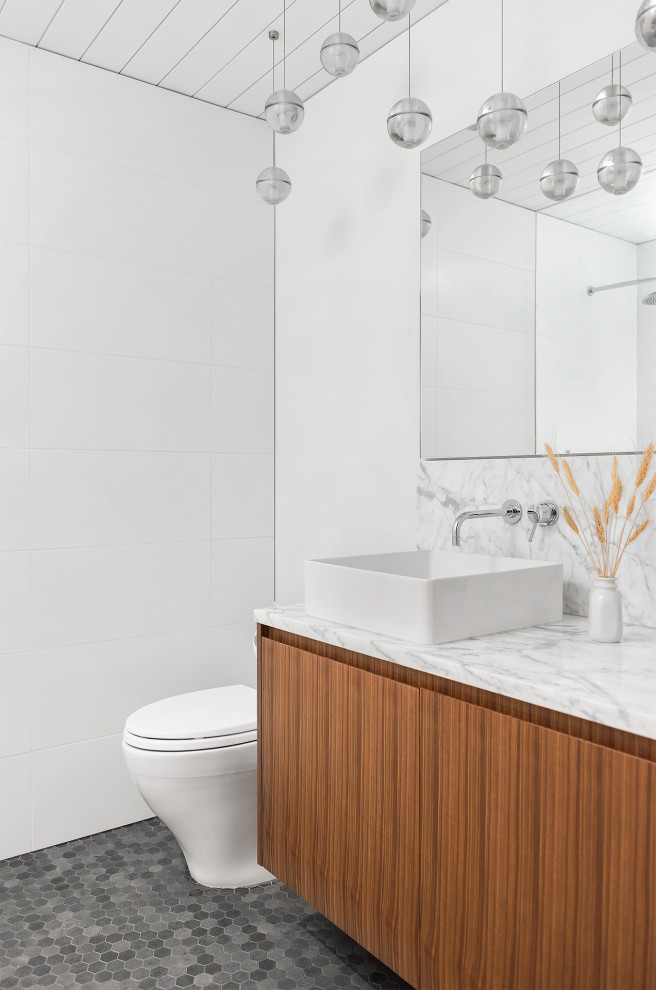 Example of a large trendy 3/4 white tile and cement tile mosaic tile floor, black floor, single-sink and shiplap ceiling toilet room design in Vancouver with flat-panel cabinets, medium tone wood cabinets, a one-piece toilet, white walls, a vessel sink, quartzite countertops, white countertops and a floating vanity