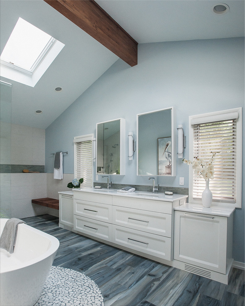 Пример оригинального дизайна: большая главная ванная комната в стиле модернизм с фасадами в стиле шейкер, белыми фасадами, отдельно стоящей ванной, душем без бортиков, раздельным унитазом, бежевой плиткой, керамогранитной плиткой, синими стенами, полом из керамогранита, врезной раковиной, столешницей из искусственного кварца, синим полом, открытым душем и белой столешницей