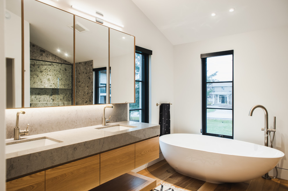 Modernes Badezimmer En Suite mit flächenbündigen Schrankfronten, hellen Holzschränken, freistehender Badewanne, weißer Wandfarbe, hellem Holzboden und Unterbauwaschbecken in Toronto