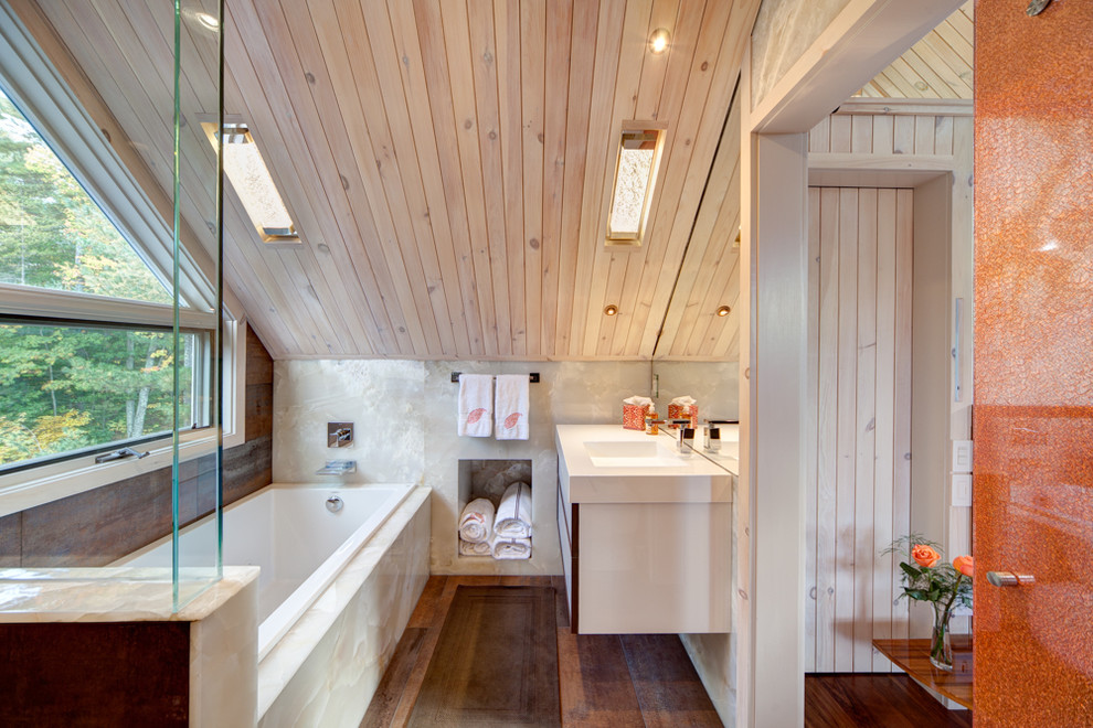 Imagen de cuarto de baño contemporáneo con bañera encastrada, suelo de madera oscura y lavabo suspendido