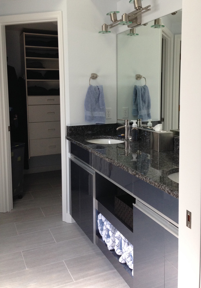 Modern inredning av ett badrum, med ett undermonterad handfat, blå skåp, granitbänkskiva, en öppen dusch, svart kakel, vita väggar och klinkergolv i porslin