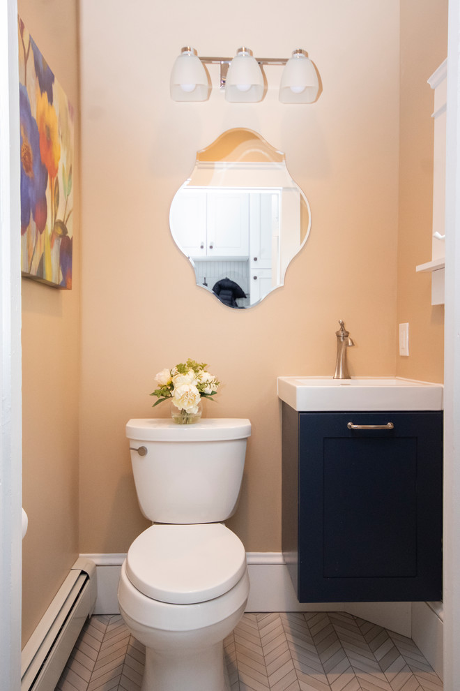 Modelo de cuarto de baño moderno pequeño con armarios con paneles lisos, puertas de armario azules, sanitario de dos piezas, paredes beige, suelo de baldosas de porcelana, aseo y ducha, lavabo suspendido, suelo gris y encimeras blancas