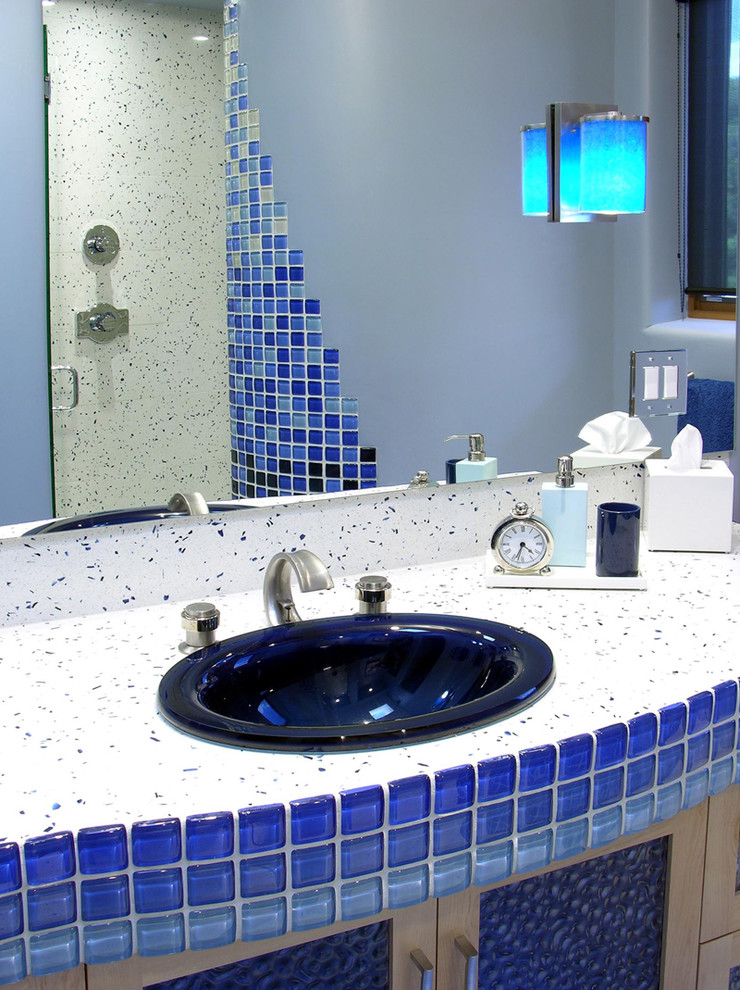 Immagine di una stanza da bagno per bambini moderna di medie dimensioni con lavabo da incasso, ante di vetro, ante in legno chiaro, top in quarzo composito, doccia aperta, piastrelle blu, piastrelle di vetro e pareti blu