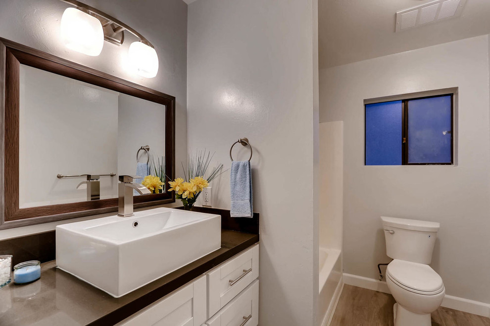 Aménagement d'une salle de bain moderne de taille moyenne avec un placard à porte shaker, des portes de placard blanches, une baignoire en alcôve, WC séparés, un mur gris, parquet clair, une vasque, un plan de toilette en quartz modifié, un sol gris et aucune cabine.