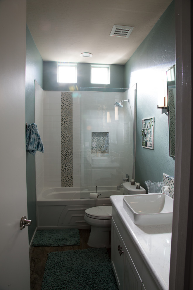 Idée de décoration pour une petite salle d'eau marine avec des portes de placard blanches, une baignoire en alcôve, un combiné douche/baignoire, un carrelage blanc, des carreaux de porcelaine, un mur bleu, un sol en carrelage de porcelaine, une vasque et un plan de toilette en quartz.