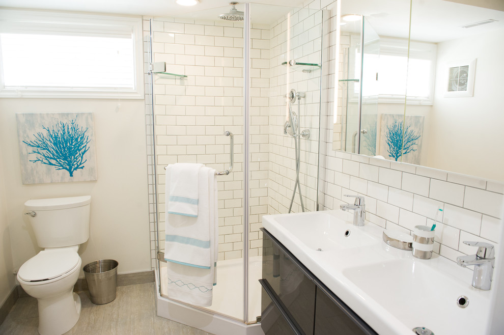 Exempel på ett mellanstort modernt badrum med dusch, med ett integrerad handfat, släta luckor, grå skåp, en hörndusch, en toalettstol med hel cisternkåpa, vit kakel, porslinskakel, vita väggar, klinkergolv i keramik, bänkskiva i kvarts, grått golv och dusch med gångjärnsdörr