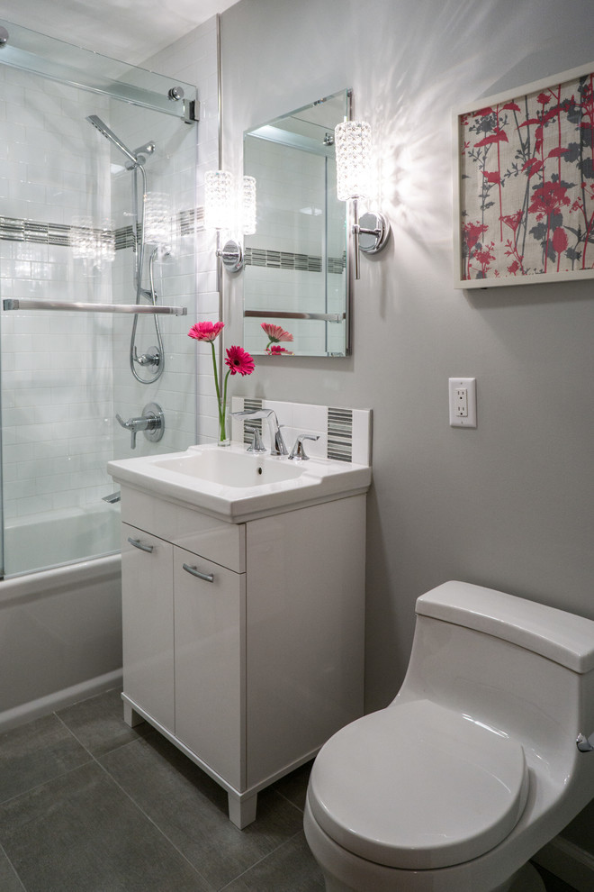 Small modern ensuite bathroom in Bridgeport with flat-panel cabinets, white cabinets, a built-in bath, a shower/bath combination, a one-piece toilet, white tiles, ceramic tiles, grey walls, cement flooring and a console sink.