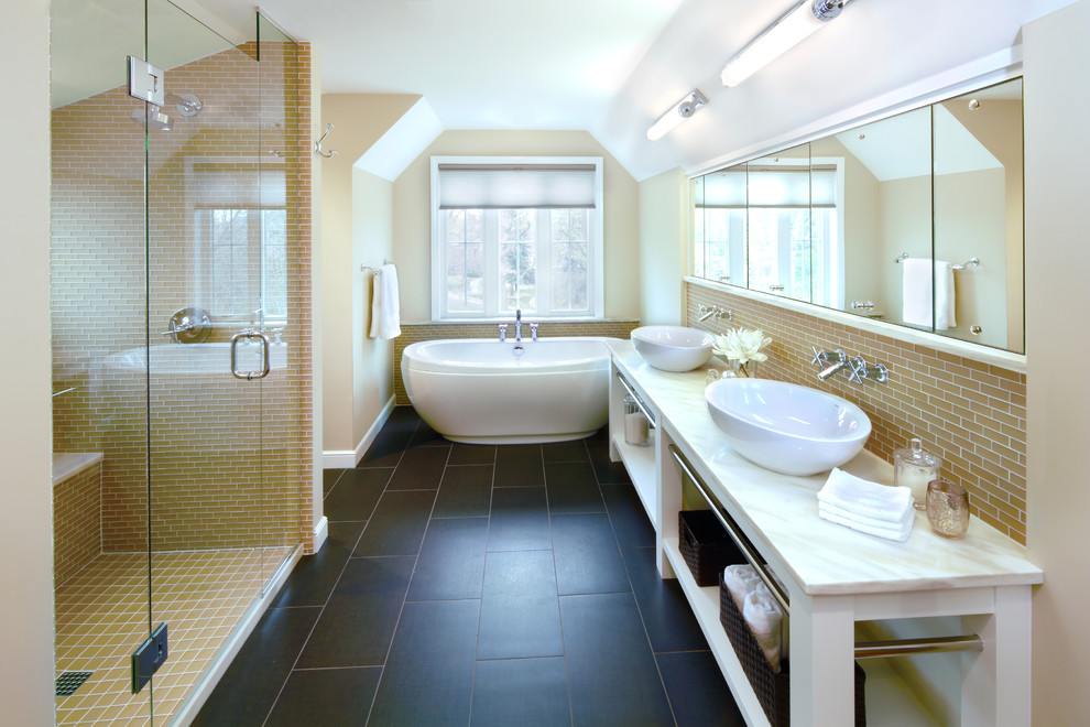 Foto på ett vintage badrum, med ett fristående badkar, ett fristående handfat, gul kakel, beige väggar och svart golv