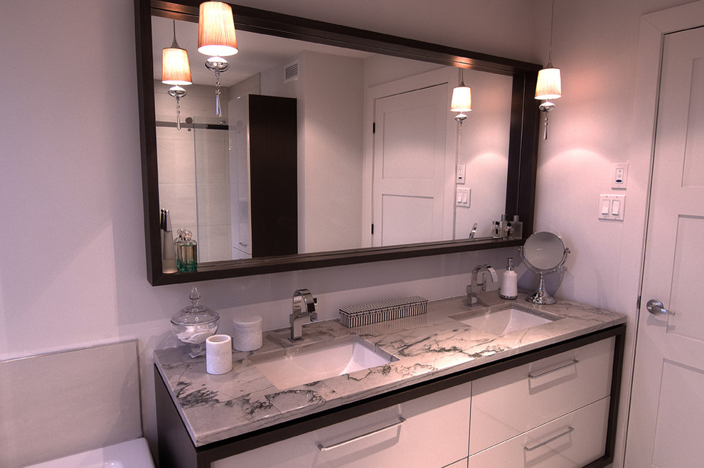 Cette image montre une salle de bain design en bois foncé avec un lavabo encastré, une baignoire d'angle, une douche d'angle, un placard à porte plane, un plan de toilette en granite, un carrelage beige, des carreaux de porcelaine, un mur gris et un sol en carrelage de porcelaine.