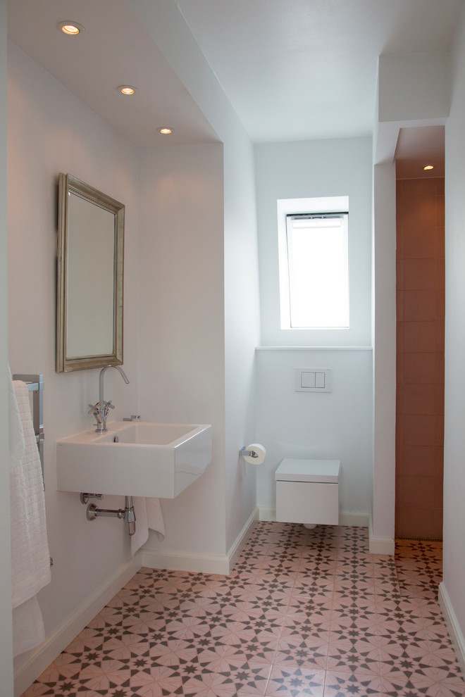 Ejemplo de cuarto de baño infantil contemporáneo de tamaño medio con ducha empotrada, sanitario de pared, baldosas y/o azulejos rosa, suelo con mosaicos de baldosas y lavabo suspendido