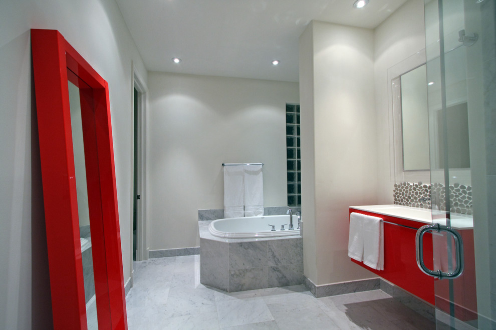 Immagine di una stanza da bagno design con ante lisce, ante rosse, vasca da incasso e piastrelle grigie