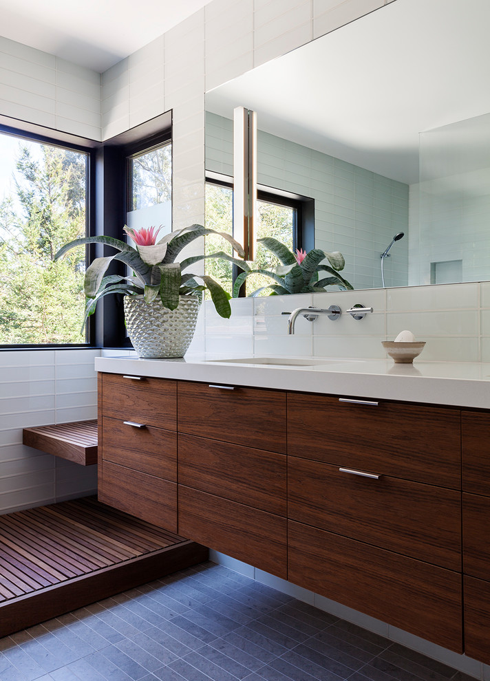 Immagine di una stanza da bagno contemporanea con ante lisce, ante in legno bruno, piastrelle bianche, piastrelle di vetro, lavabo sottopiano e pavimento grigio